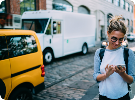 A lady standing and using her phone on a busy street