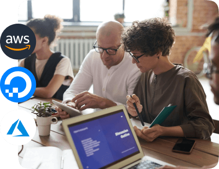 four individuals in a modern office setting engaged in a collaborative work session involving cloud hosting highlighting AWS, DigitalOcean and Microsoft Azure. 