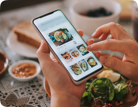 A food delivery app in hand where the user is taping on the screen to explore a dish